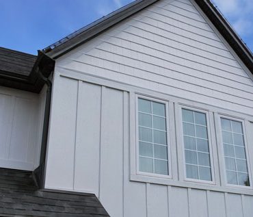 Second Story View of a Modern Farmhouse Style House with 3 Large Windows with White Grilles and Engineered Wood Exterior Trim.