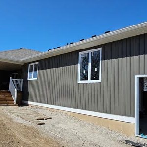 Image of the back view of a custom exterior finishing project completed by Aurora Exteriors Inc, featuring verical vinyl in a Castlemore Colour and Versetta Stone Siding in sterling.