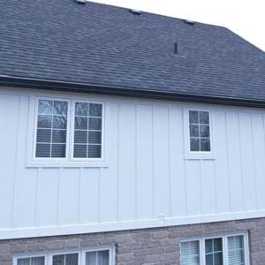 Back Side View of a Tudor Home, refaced to ressemble a Modern Farmhouse Style home with white board and batten siding with black trims.