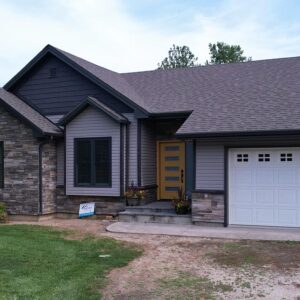 Front Facade of a recently renovated home featuring stone siding accents for timeless character and a beautiful autumn yellow entry door.