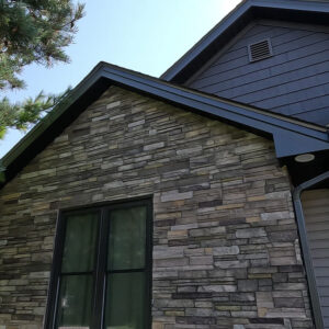 Dark Sterling Versetta Stone Siding Accent adds character to an architectural feature on the front face of a home recently renovated by Aurora Exteriors Inc.