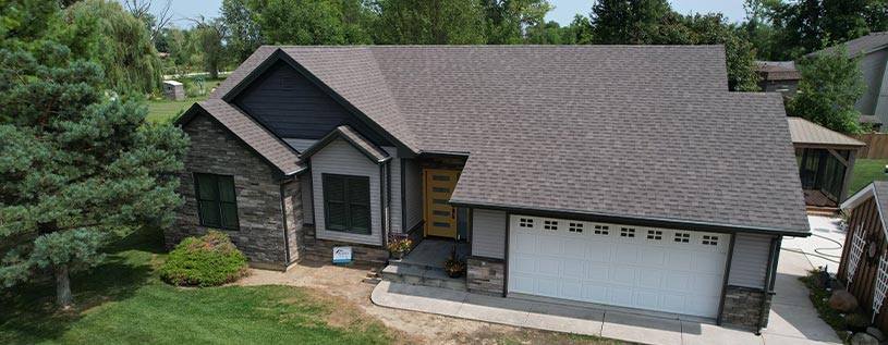 Overhead View of A Home After a Complete exterior makeover by Aurora Exteriors Inc, featuring stone siding accents in a dark Sterling colour and dark stonecrest grey vinyl siding with manor shakes in the gables.
